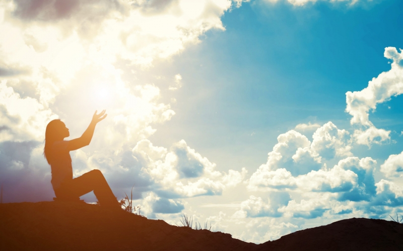 Silhouette of woman praying over beautiful sunrise background Silhouette of woman praying over beautiful sunrise background